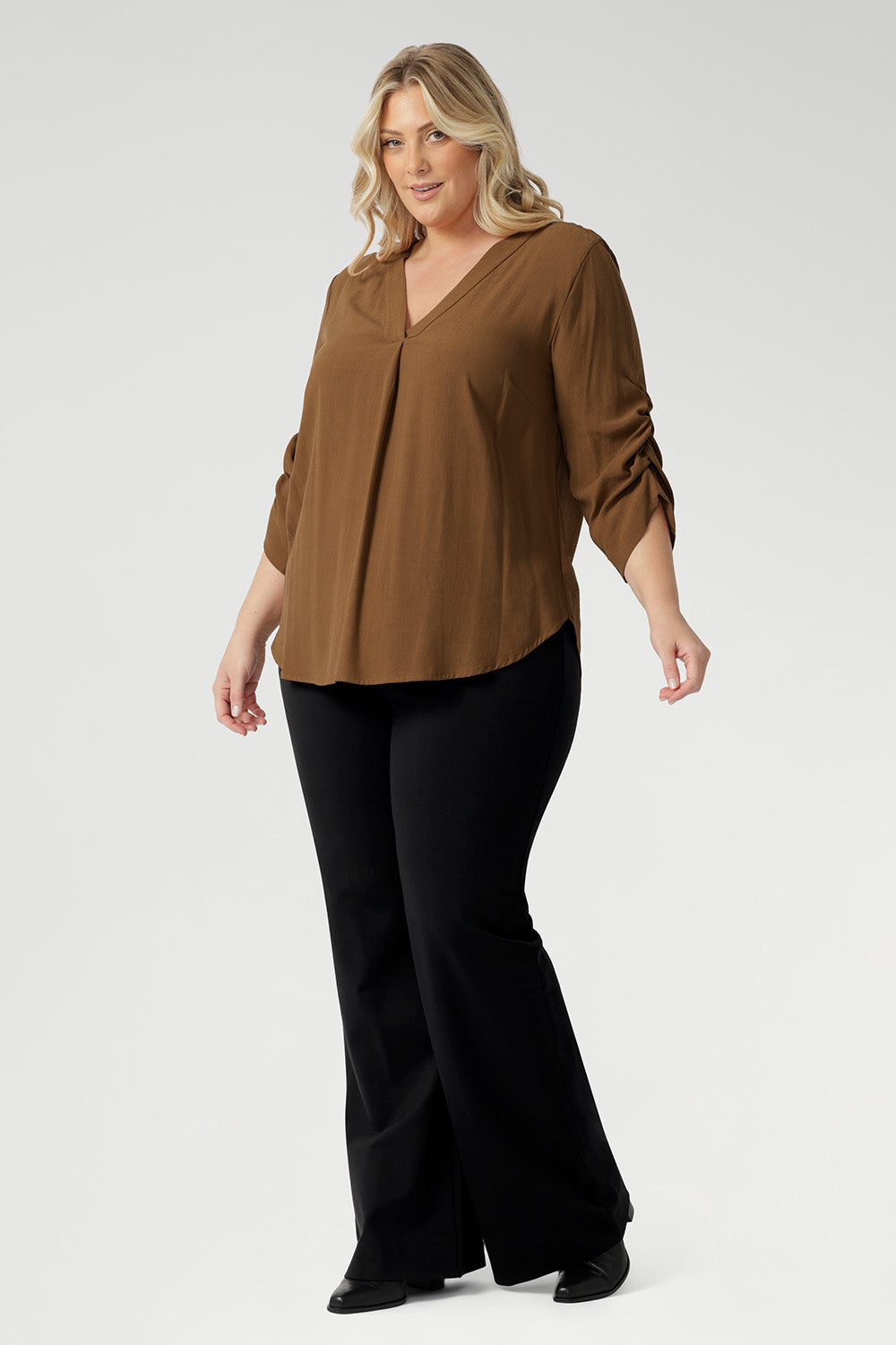 The elegant V-neckline features a tailored tuck at the centre front, while the back is finished with a subtle pleat for a touch of structure and flow. With beautifully ruched ¾ sleeves. Worn by size 18 woman worn with black bootleg pants. 